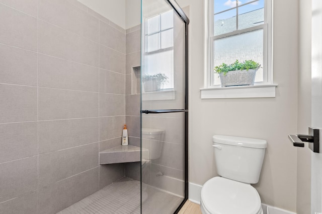 bathroom featuring a shower with door and toilet