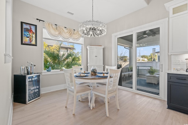 dining space featuring a notable chandelier, a healthy amount of sunlight, and light wood-type flooring