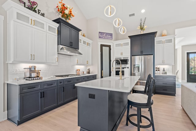 kitchen featuring white cabinetry, appliances with stainless steel finishes, an island with sink, and light wood-type flooring