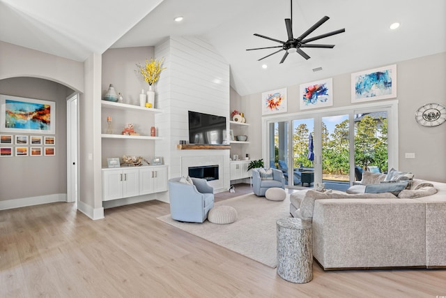 living room with a fireplace, high vaulted ceiling, ceiling fan, and light wood-type flooring