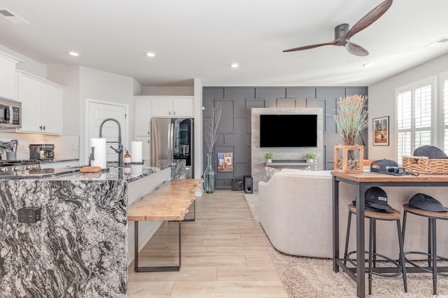 kitchen with a kitchen breakfast bar, white cabinetry, dark stone counters, and stainless steel appliances