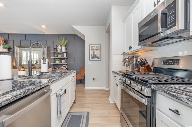 kitchen with sink, white cabinetry, dark stone countertops, and stainless steel appliances