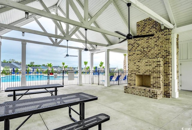 view of patio / terrace featuring an outdoor brick fireplace, a community pool, and ceiling fan