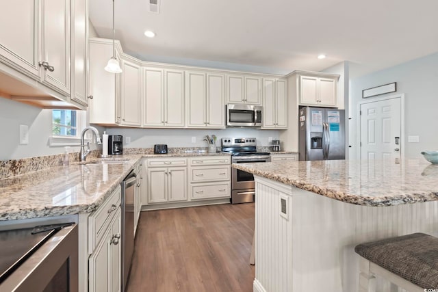 kitchen featuring pendant lighting, dark hardwood / wood-style flooring, stainless steel appliances, sink, and light stone counters