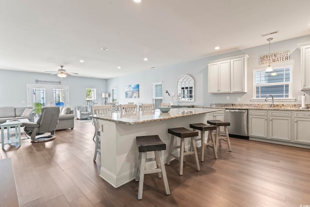 kitchen featuring wood-type flooring, dishwasher, decorative light fixtures, a kitchen bar, and a kitchen island