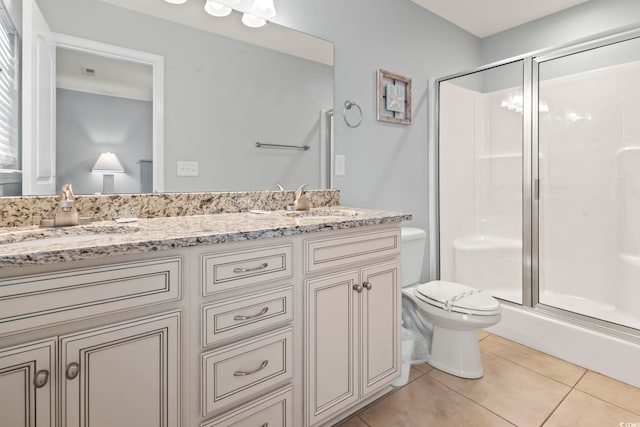 bathroom featuring toilet, vanity, tile patterned floors, and an enclosed shower