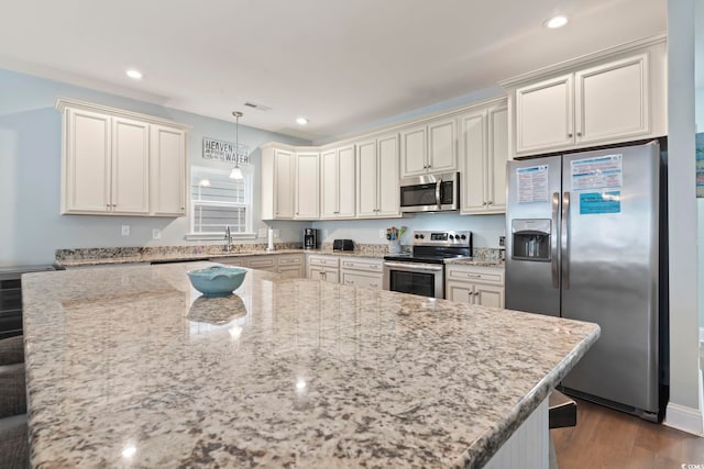 kitchen with decorative light fixtures, sink, light stone counters, and stainless steel appliances