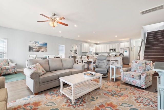 living room featuring ceiling fan, light hardwood / wood-style flooring, and plenty of natural light