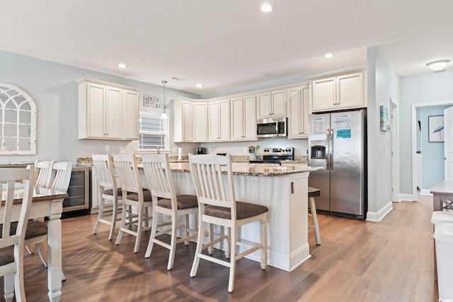 kitchen with a center island, appliances with stainless steel finishes, a kitchen breakfast bar, dark stone countertops, and pendant lighting