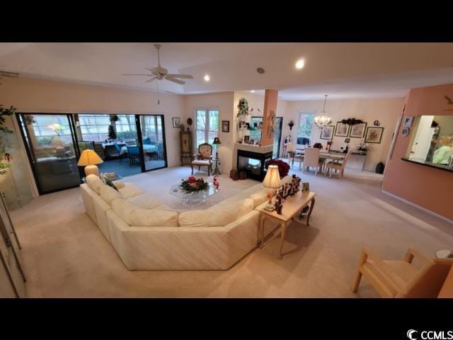 carpeted living room featuring ceiling fan with notable chandelier