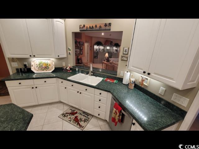 kitchen with white cabinetry, sink, stainless steel dishwasher, and light tile patterned flooring