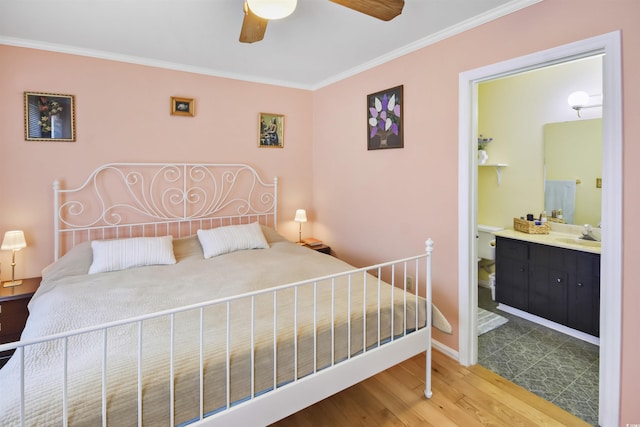 bedroom featuring ensuite bath, sink, hardwood / wood-style flooring, ornamental molding, and ceiling fan