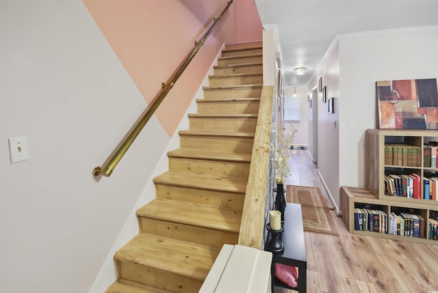 stairs with wood-type flooring and ornamental molding