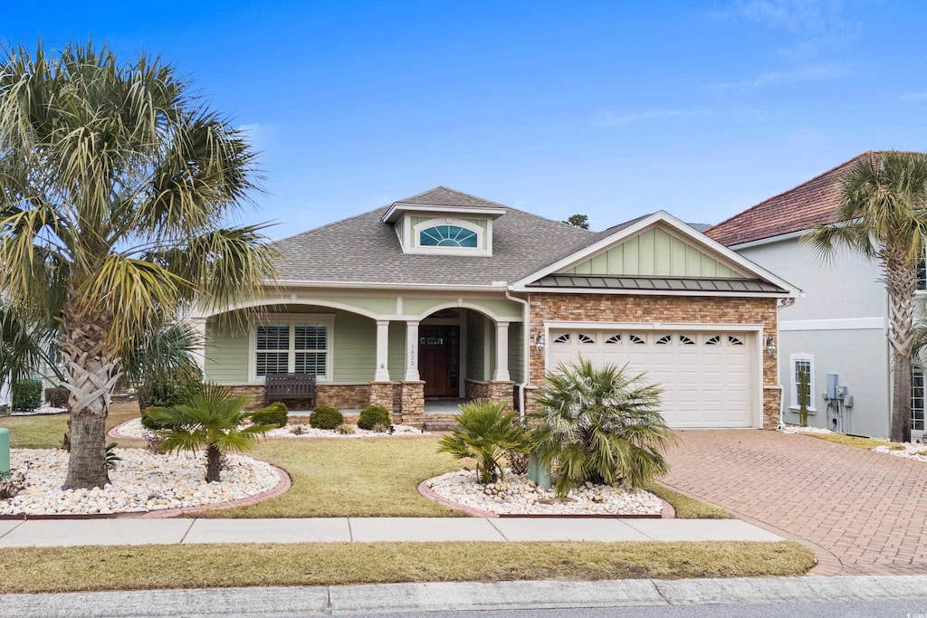 view of front of home featuring a garage, covered porch, and a front yard