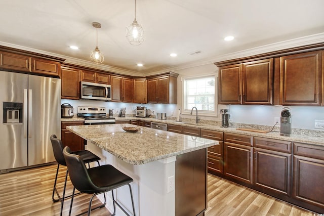 kitchen with a center island, appliances with stainless steel finishes, sink, decorative light fixtures, and ornamental molding