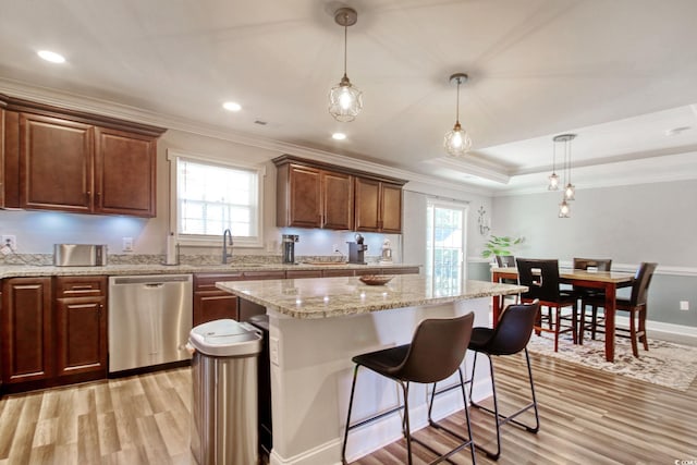 kitchen with dishwasher, hanging light fixtures, a tray ceiling, a center island, and light hardwood / wood-style floors