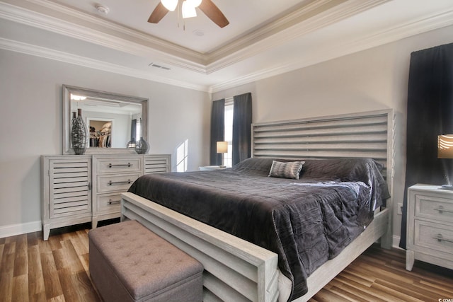 bedroom featuring wood-type flooring, a raised ceiling, ceiling fan, and ornamental molding