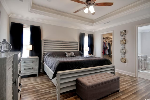 bedroom featuring a walk in closet, ceiling fan, ornamental molding, and wood-type flooring