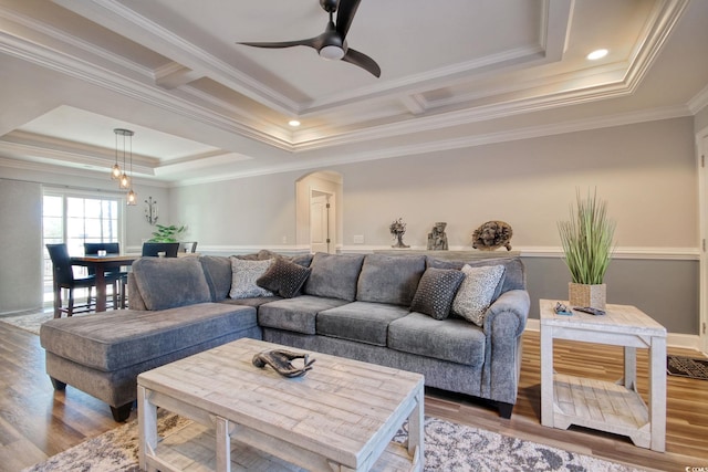 living room featuring ceiling fan, a tray ceiling, light hardwood / wood-style flooring, and crown molding