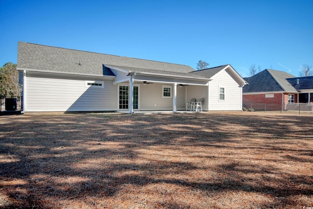 back of property with ceiling fan and a yard