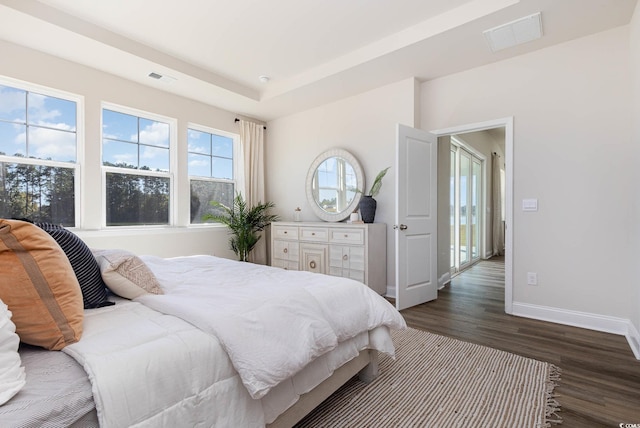 bedroom with a tray ceiling and dark hardwood / wood-style flooring