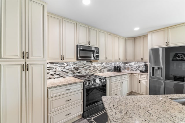 kitchen featuring light stone counters, backsplash, stainless steel appliances, and cream cabinets