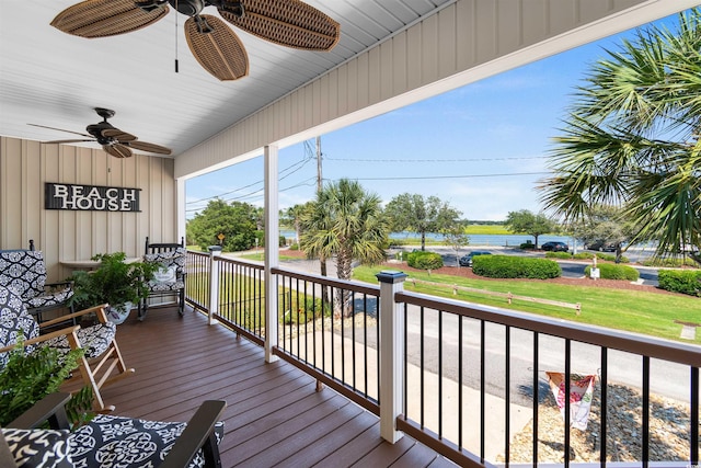 wooden deck featuring covered porch, ceiling fan, and a water view