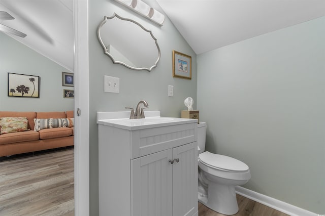 bathroom with hardwood / wood-style floors, toilet, lofted ceiling, and vanity