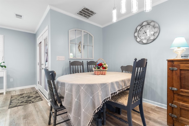 dining room featuring light hardwood / wood-style floors and crown molding