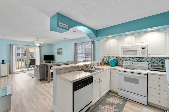 kitchen featuring sink, white appliances, white cabinetry, and kitchen peninsula