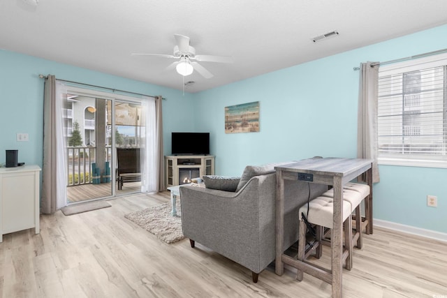 living room featuring light wood-type flooring, a textured ceiling, and ceiling fan