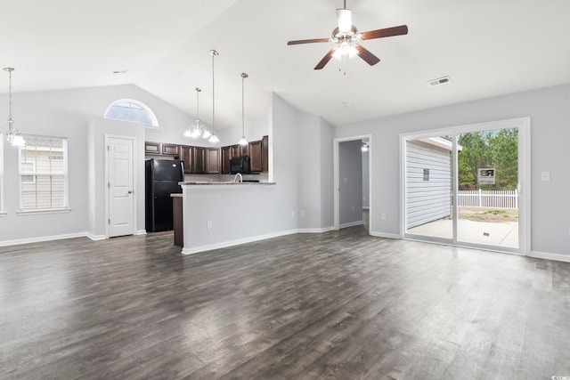 unfurnished living room with dark wood-type flooring, ceiling fan with notable chandelier, and high vaulted ceiling