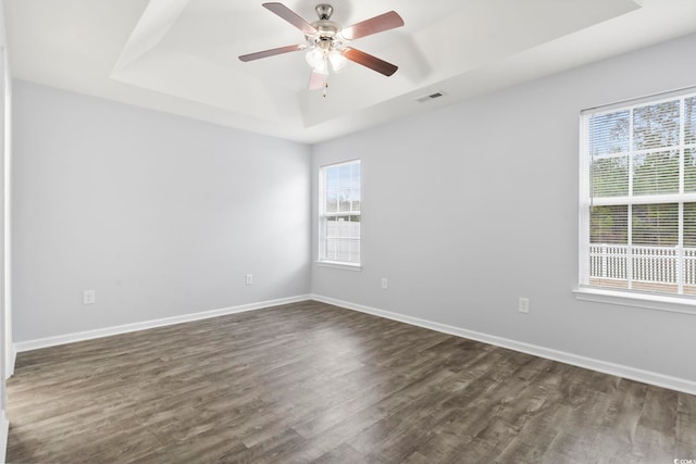 unfurnished room with ceiling fan, dark hardwood / wood-style flooring, and a raised ceiling