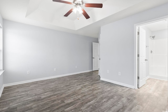 unfurnished bedroom featuring ceiling fan, dark hardwood / wood-style flooring, and a raised ceiling