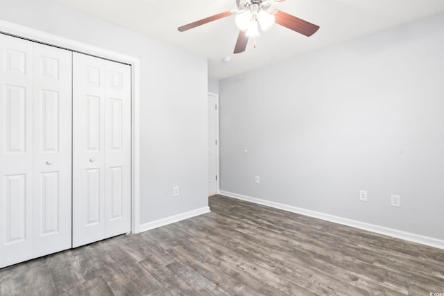 unfurnished bedroom with dark wood-type flooring, a closet, and ceiling fan