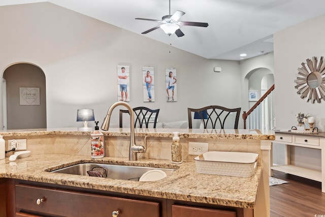 kitchen with vaulted ceiling, ceiling fan, sink, dark wood-type flooring, and light stone countertops