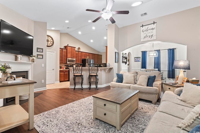 living room with ceiling fan, light hardwood / wood-style flooring, and high vaulted ceiling