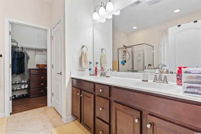 bathroom featuring a shower with shower door, vanity, and tile patterned flooring