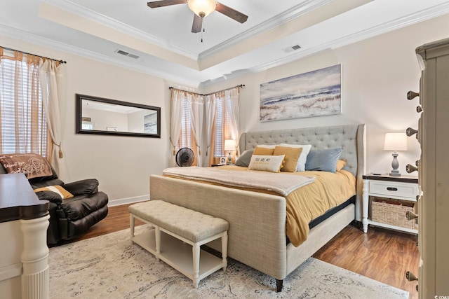 bedroom featuring hardwood / wood-style floors, a tray ceiling, ceiling fan, and ornamental molding