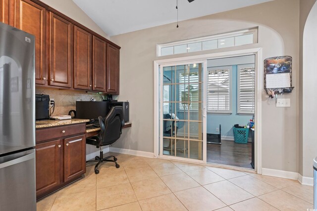 tiled home office featuring ceiling fan, built in desk, and vaulted ceiling