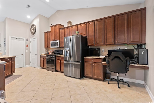 kitchen with light tile patterned floors, tasteful backsplash, vaulted ceiling, and appliances with stainless steel finishes