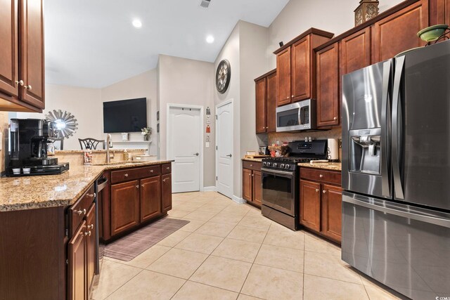 kitchen with light stone countertops, stainless steel appliances, decorative backsplash, sink, and light tile patterned floors