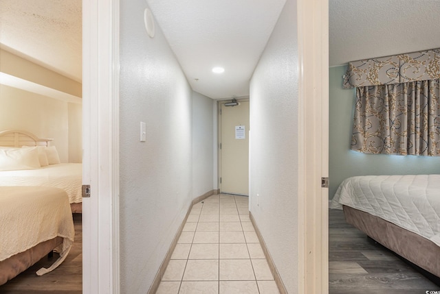 hall featuring light tile patterned flooring and a textured ceiling