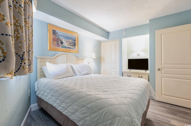 bedroom with a textured ceiling, a closet, and hardwood / wood-style floors