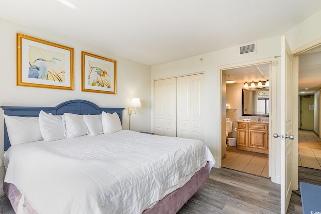 bedroom featuring hardwood / wood-style floors, a closet, and ensuite bath