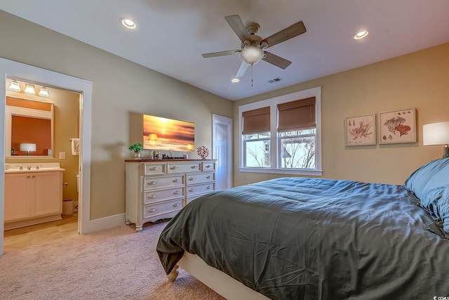 bedroom with light carpet, sink, ceiling fan, and ensuite bathroom