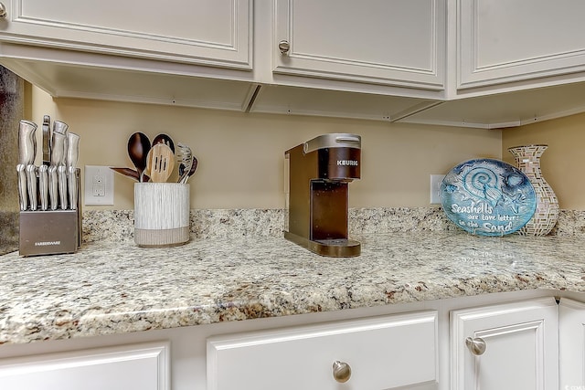 interior details featuring white cabinetry and light stone countertops