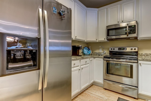 kitchen featuring appliances with stainless steel finishes, white cabinets, and light stone counters