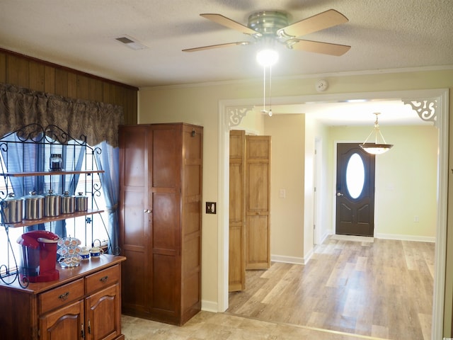 entrance foyer with crown molding, a textured ceiling, and light hardwood / wood-style flooring