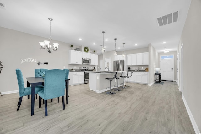 dining space with an inviting chandelier, sink, and light hardwood / wood-style floors